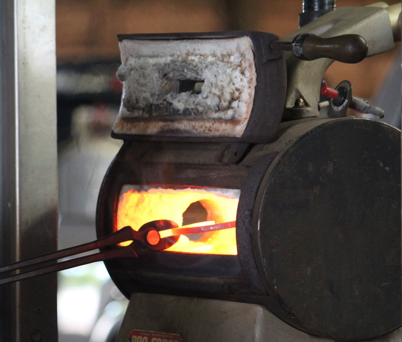 Student shaping a shoe at the forge